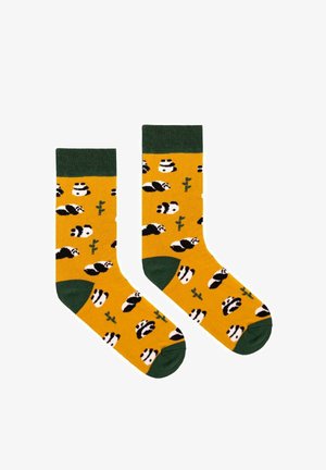 Żółte skarpety z zielonym mankietem, ozdobione wzorem czarno-białych pand i zielonymi akcentami bambusa. Wykonane z miękkiego, elastycznego materiału.