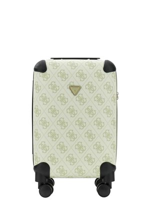 Valise rigide couleur crème avec motif monogramme, protections d’angle noires, quatre roues pivotantes et plaque de logo triangulaire à l’avant.