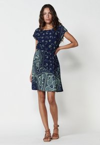 Rochie bleumarin cu mâneci scurte, cu modele paisley și geometrice în verde. Talie elastică și fustă evazată. Textură de țesătură netedă.