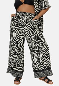 Zwart-witte zebra-gestreepte wijde broek met een elastische tailleband, voorzien van zijzakken en een patroon aan de onderkant. Lichtgewicht materiaal.