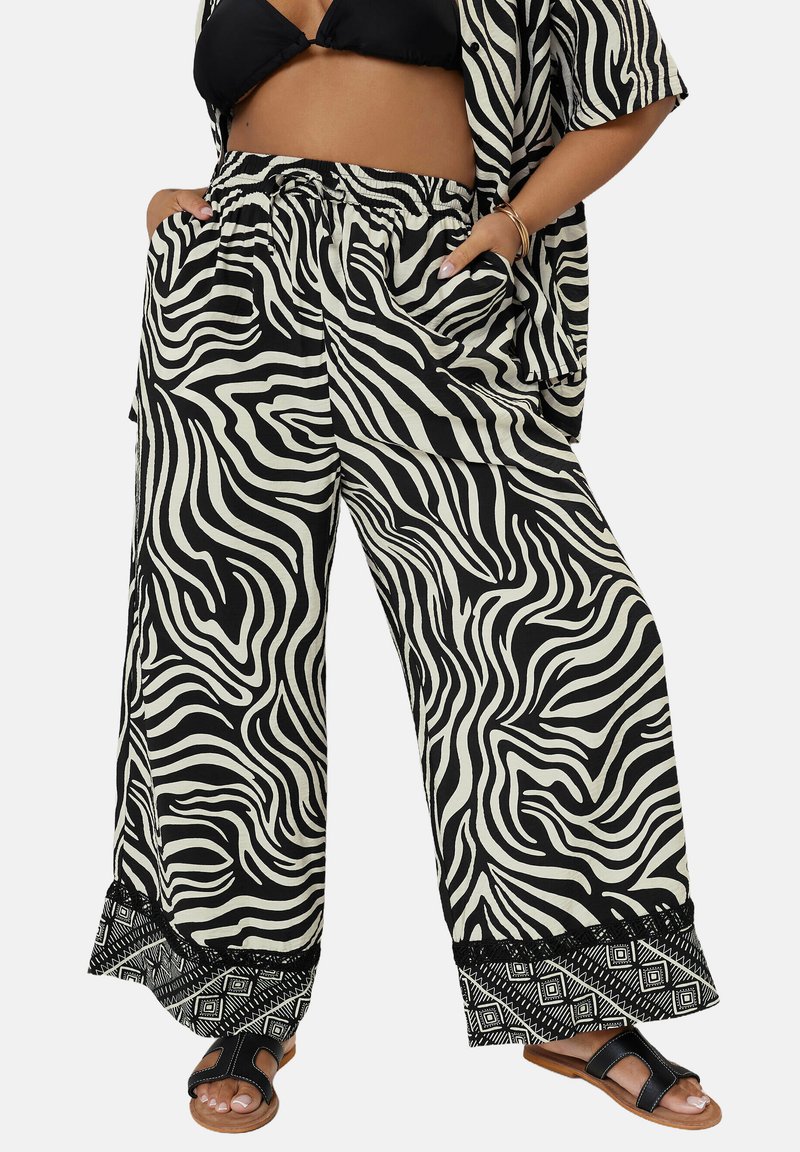 Zwart-witte zebra-gestreepte wijde broek met een elastische tailleband, voorzien van zijzakken en een patroon aan de onderkant. Lichtgewicht materiaal.