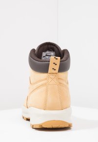Bottines en daim beige avec un col rembourré brun foncé, dos renforcé et une languette. Semelle blanche avec une base en caoutchouc texturé pour une meilleure adhérence.