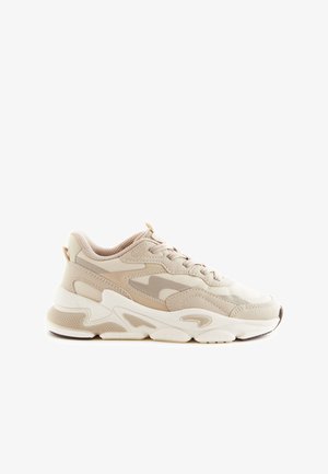 Sneaker atletiche beige caratterizzate da una combinazione di materiali lisci e testurizzati, punta arrotondata, suola spessa e design con lacci con accenti sottili.