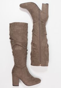 Knee-high taupe faux suede boots with a chunky heel, slouchy design, side zipper, and smooth texture. Features gold-tone hardware accent.