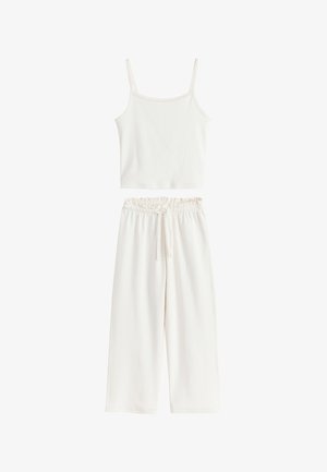 Weißes ärmelloses Crop-Top mit dünnen Trägern, kombiniert mit lockeren, hoch taillierten weißen Hosen mit elastischem Bund und Kordelzug.