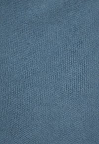 Prim-plan al unui material textil tricotat, de culoare albastră, cu un model de cusătură diagonală și o suprafață moale, uniformă.