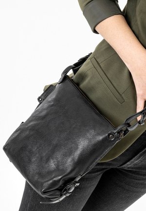 Black leather crossbody bag with a zippered closure and woven strap, featuring a smooth texture and minimalist design.