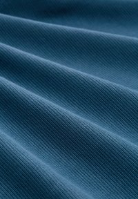 Gestructureerde blauwe stof met zichtbaar ribbelpatroon, dat zachte golven en een uniforme kleur over het oppervlak toont.