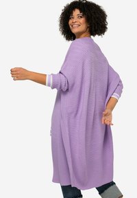 Ljuslila stickad cardigan med ribbad struktur och sidoflikar. Har kontrasterande randiga ärmslut och en loose fit.