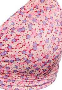 Bikini zgornji del z cvetličnim vzorcem v roza, rdečih in modrih odtenkih. Gladek, elastičen material z nabranjem ob spodnjem robu, ki vsebuje majhne cvetlične vzorce.