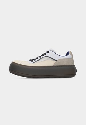 Sneaker bassa con suola spessa di colore scuro, tomaia bianca con dettagli in suede beige e grigio, lacci neri e fodera interna blu scuro.