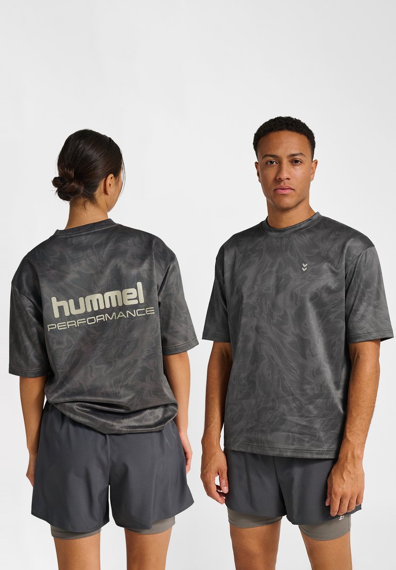 Zwei Modelle tragen passende dunkelgraue Sportshirts und Shorts; eines schaut nach vorne, das andere zeigt das "hummel PERFORMANCE"-Logo auf dem Rücken.