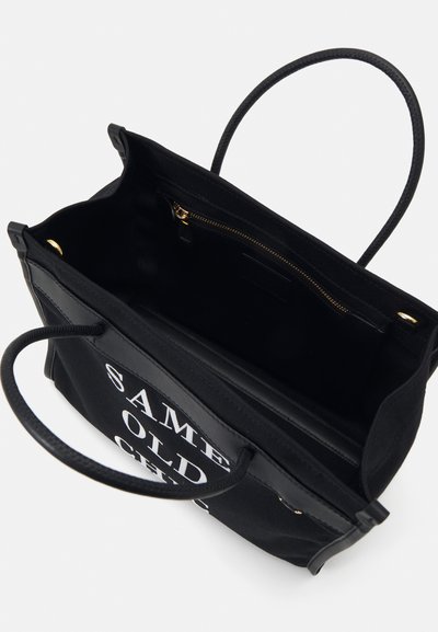 Must mustrepp kott mustrepp nahkakomplektiga. Omab avatud ülemust, kahte käepidet ja sisemist tõmblukuga taskut. Näidustustekst: "SAMA VANAD SAGEDAD."