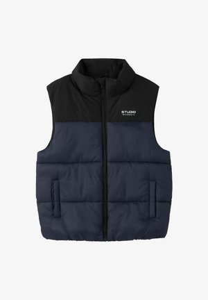Gilet matelassé sans manches avec partie supérieure noire et partie inférieure bleu marine, fermeture éclair avant, deux poches et logo "STUDIO Outdoors" sur la poitrine.