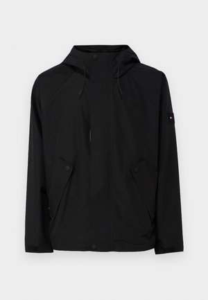 Schwarze Windbreaker-Jacke mit Kapuze, ausgestattet mit Druckknöpfen und zwei Fronttaschen. Hergestellt aus glattem, wasserabweisendem Stoff.