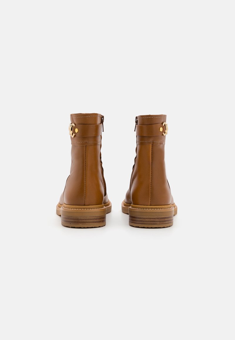 Bruine leren enkellaarzen met een gestructureerde afwerking, zijkettingen en accenten van goudkleurig hardware. Gestapelde houten hakken, eenvoudig ontwerp.