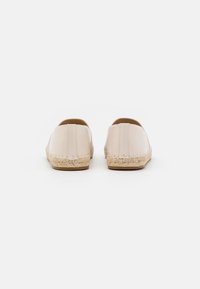 Espadrillas rosa chiaro con tomaia in pelle liscia, suola intermedia intrecciata in juta e punta rotonda. La vista posteriore mostra un design senza cuciture e cuciture.