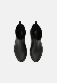 Zwarte rubberen enkellaarzen met een gladde afwerking, elastische zijpanelen en een treklipje voor eenvoudig aan- en uittrekken. Van binnen gevoerd met zacht materiaal voor comfort.