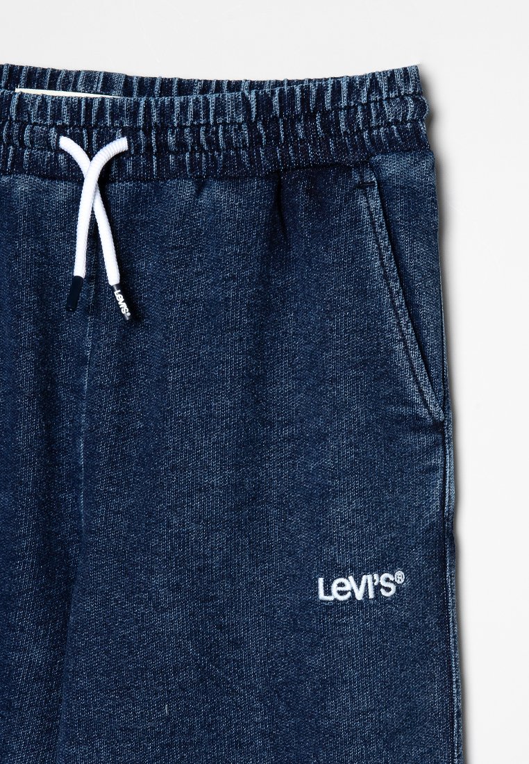 Pantalones de chándal azul marino hechos de una tela suave con cintura con cordón, que cuentan con bolsillos laterales y un logo de Levi's bordado en blanco en la pierna.