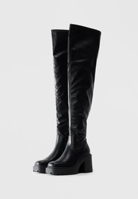 Black over-the-knee boots with a sleek, smooth faux leather finish. Chunky block heel and textured sole. Side zipper detail for closure.