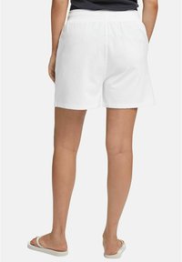 Białe bawełniane szorty z elastycznym pasem, charakteryzujące się luźnym krojem i jednolitym wzorem. Noszone z sandałami na płaskiej podeszwie.
