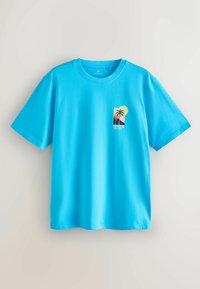 T-shirt à manches courtes bleu vif avec un petit motif de palmiers, un soleil et le mot « NICE » sur le côté gauche de la poitrine.