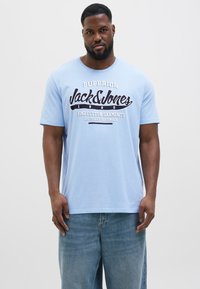 Svetle modré bavlněné tričko s výrazným černobílým grafickým potiskem s nápisem "Jack & Jones" a "Fine Cotton Garments". Krátké rukávy.