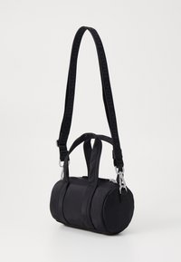 Sac en nylon noir avec double anses supérieures, une bandoulière amovible affichant un logo répété, fermeture éclair et texture lisse.