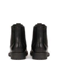 Las botas de cuero negro hasta el tobillo cuentan con paneles laterales elásticos, una puntera redondeada y una suela de goma texturizada con un tacón bajo.
