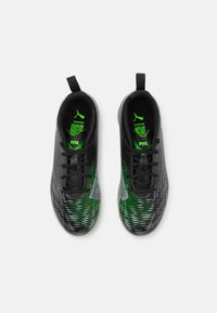 Schwarze und grüne Fußballschuhe mit strukturiertem Obermaterial, dynamischem Streifenmuster, Schnürverschluss und Zuglaschen. PUMA-Logo an der Seite.
