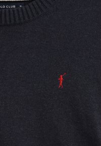 Maglione blu navy in maglia con colletto a girocollo a coste e una piccola figura rossa ricamata sul lato sinistro del petto. Tessuto morbido, design casual.