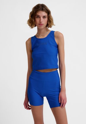 Blue athletic crop top and high-waisted shorts made of smooth fabric; features logo detail on the top and a fitted design.