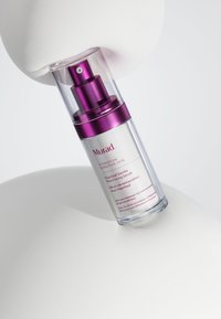 Sérum doux de resurfaçage Murad Heartleaf dans un flacon transparent avec un capuchon à pompe violet, présentant des étiquettes blanches et roses. Texture lisse.