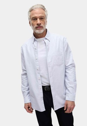 Lange mouwen button-up overhemd in lichtblauw en witte strepen, met een enkele borstzak. Draag het over een wit T-shirt en donkere broek.