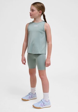 Mintgroen mouwloos topje en bijpassende fietsbroek, gemaakt van gladde stof. Het topje heeft een wit logo; sportieve schoenen in lichtblauw met paarse accenten.