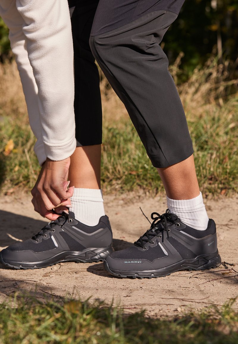 Črne pohodne čevlje z teksturirano tkanino, gumijastimi podplati in vezalkami. Imajo srebrne poudarke in trpežno zasnovo, primerno za dejavnosti na prostem.