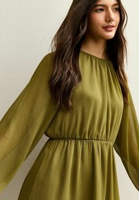 Vestido plisado verde oliva con mangas largas y fluidas y cintura fruncida. Tela suave y ligera con una textura lisa.