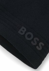Black beanie hat made from textured knit material. Features a raised "BOSS" logo in black on the cuff for a subtle design detail.