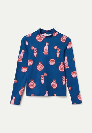 Camiseta de manga larga en tela azul con un patrón repetido de gatos rosas, jarrones y flores. Cuello alto con diseño ajustado.