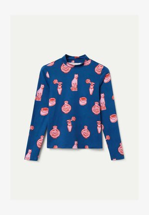 Camiseta de manga larga en tela azul con un patrón repetido de gatos rosas, jarrones y flores. Cuello alto con diseño ajustado.