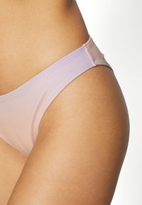 Cuecas de bikini sem emendas numa gradiente de rosa pálido a lavanda. Material suave com uma textura lisa e design minimalista.