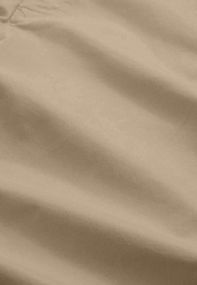 Lys beige stof med en glat tekstur; synlig syning og folder skaber et subtilt bølgemønster. Primært lavet af blødt, holdbart materiale.