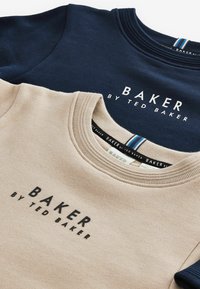 Due felpe girocollo impilate. Una blu navy, l'altra beige, entrambe con "BAKER by TED BAKER" stampato in nero sulla parte anteriore.