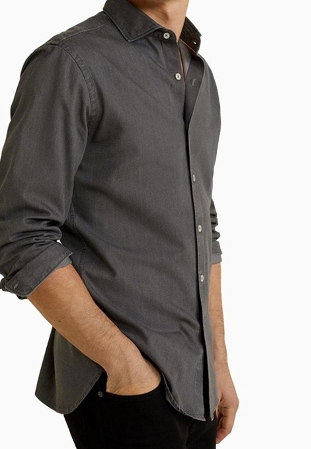 Camisa gris de botones en tela suave, con cuello abierto, mangas largas con puños doblados y dobladillo ligeramente curvado.