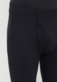 Μαύρο κολάν από ριγωτό ύφασμα με πλαϊνή τσέπη και εφαρμοστή σχεδίαση. Λείο υλικό με ελαστική μέση.