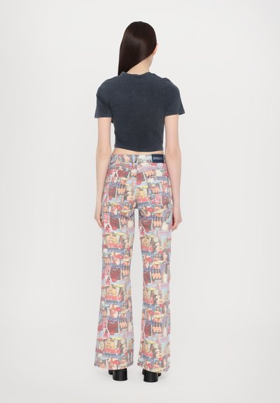 Flared jeans with a colorful collage print. Made of denim, featuring a high waist and a smooth texture. Accompanied by a fitted gray top.