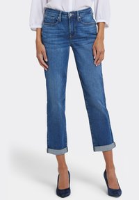 Blå denimjeans med rak skärning och uppvikta fållar. Har en klassisk design med fem fickor och knäppning framtill.