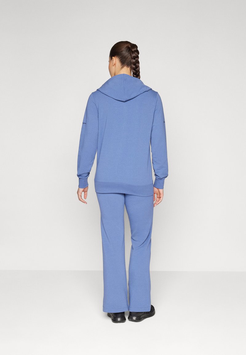Felpa blu con cappuccio e pantaloni abbinati, realizzati in tessuto morbido; presenta un cappuccio, maniche lunghe e una vestibilità comoda con gambe svasate.