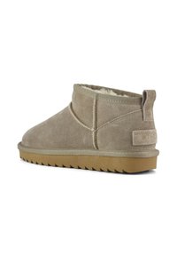 Beige Wildleder-Ankle Boots mit runder Zehenpartie, weichem Fellfutter und strukturierter Gummisohle. Mit einem kleinen, markierten Tag am Absatz.