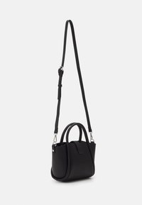 Mała czarna torebka wykonana z teksturowanego materiału, z podwójnymi uchwytami, regulowanym paskiem oraz minimalistycznym wzornictwem.